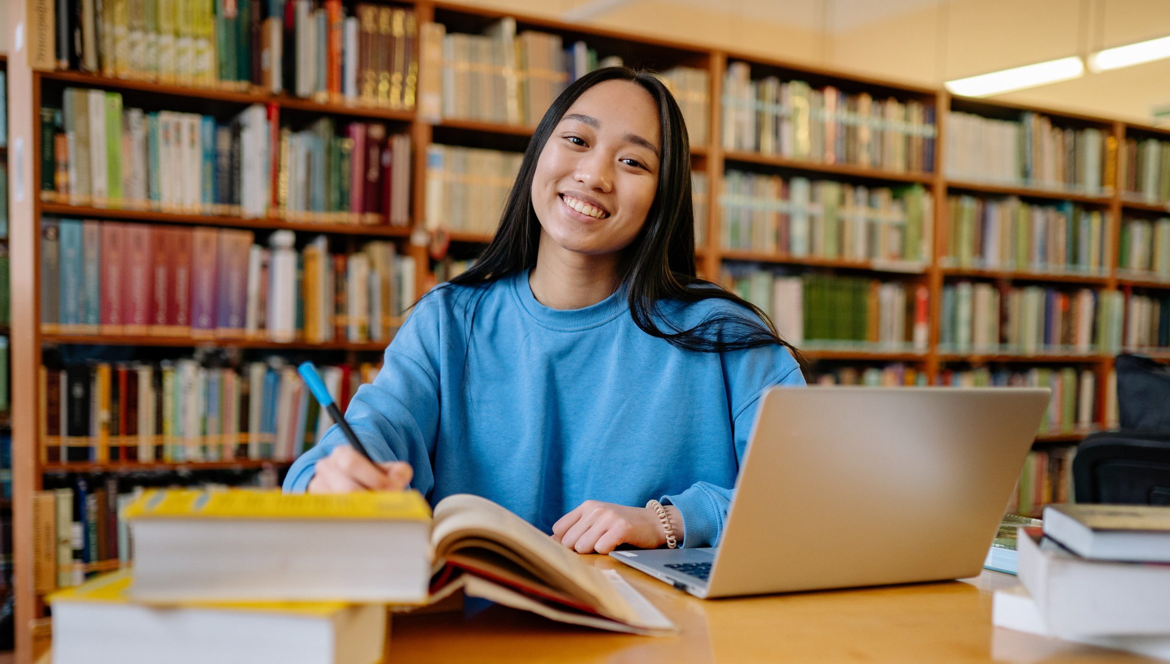 Young woman engrossed in studying and writing at a university library.